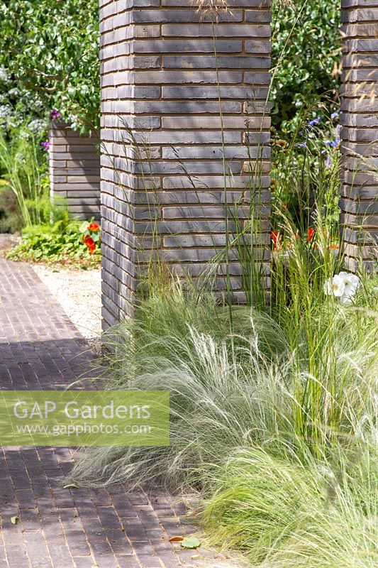 Garden with ornamental grasses divided by belgium brick paver columns and walls. RHS Sanctuary Garden - Hampton Court Flower Festival 2019 