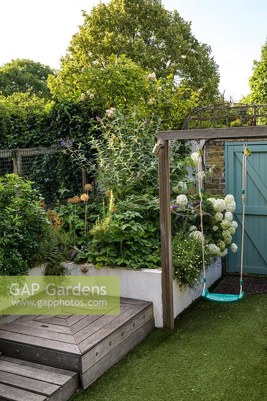 Swing and raised bed with planting with Allium, white Hydrangea and Erigeronby Earth Designs