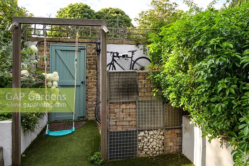 Swing and raised bed with planting gabion wall with bicycle storage by Earth Designs