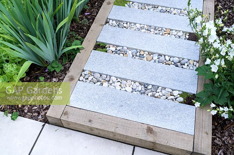 Small modern garden in London, with paving slab stepping stones in gravel infill raised pathway, by Earth Designs.
