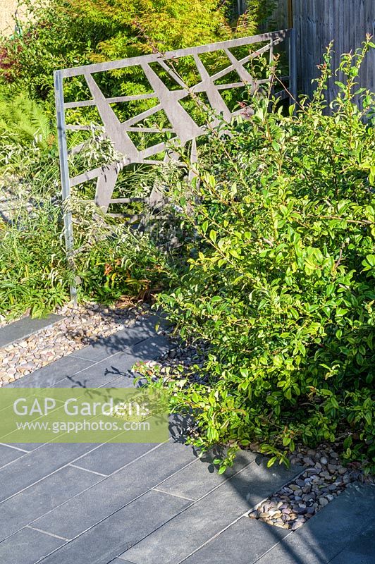 Decorative powder-coated aluminium pattern screens in shrub and perennial border in modern, North London garden by Earth Designs.