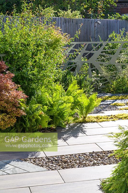 Modern Garden in North London by Earth Designs, with Ebony Cloud schist paving, Japanese polished pebbles, and planting of acers, ferns and shrubs. 