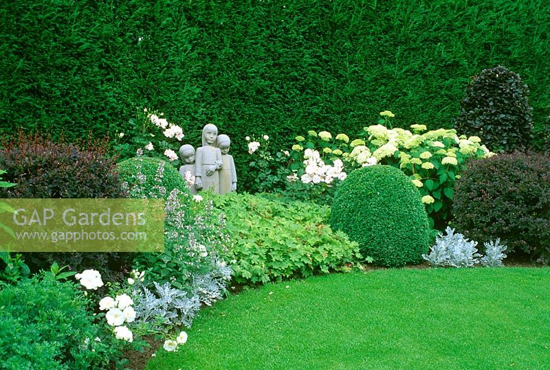 Sculpture in mixed border with shrubs and perennials. 

