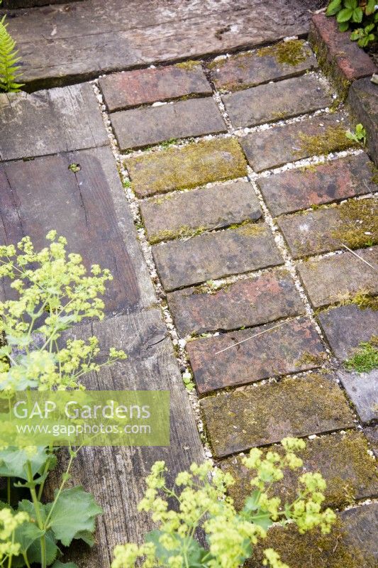 Path made of railway sleepers and bricks in a cottage garden in June