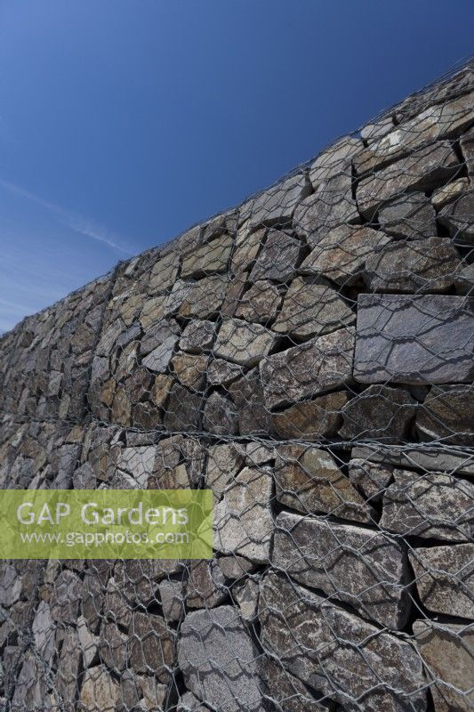 Tall gabion wall made of heavy duty galvanised wire and irregularly shaped, split olivine basalt.