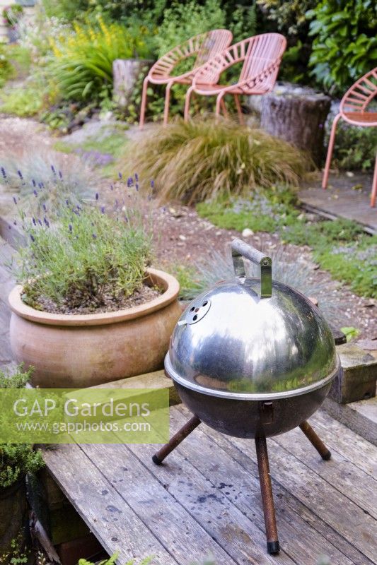 Small tripod barbecue on decking in a cottage garden in June