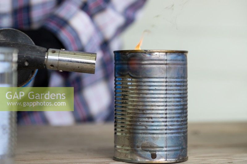 Close up shot of woman using blowtorch on a tin can