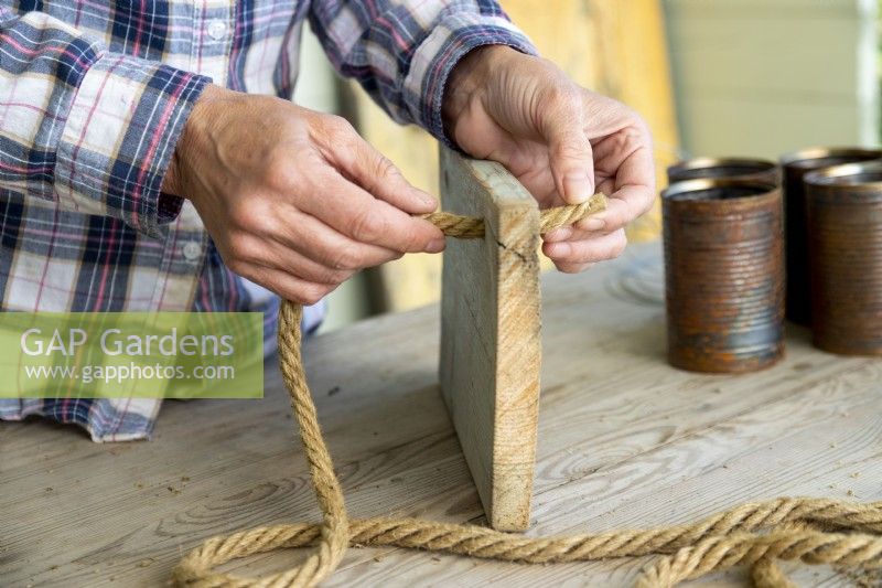 Woman feeding rope through holes in a wooden board