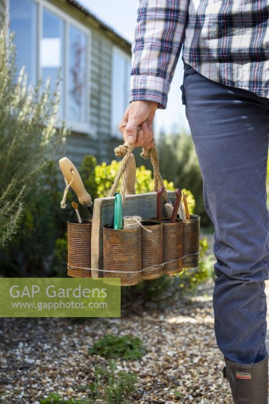 Woman carrying tin can caddy with gardening tools