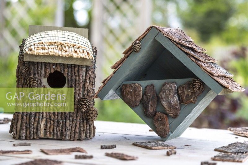 Bird houses on a wooden surface with garden in background