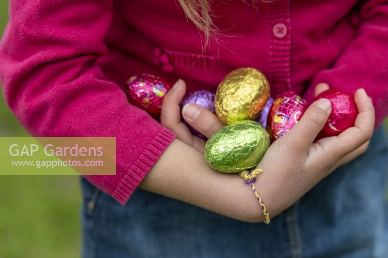 Child holding colourful chocolate eggs at Easter