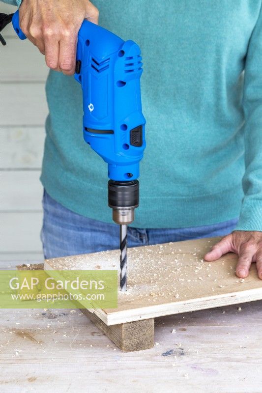 Woman drilling holes in the wooden board
