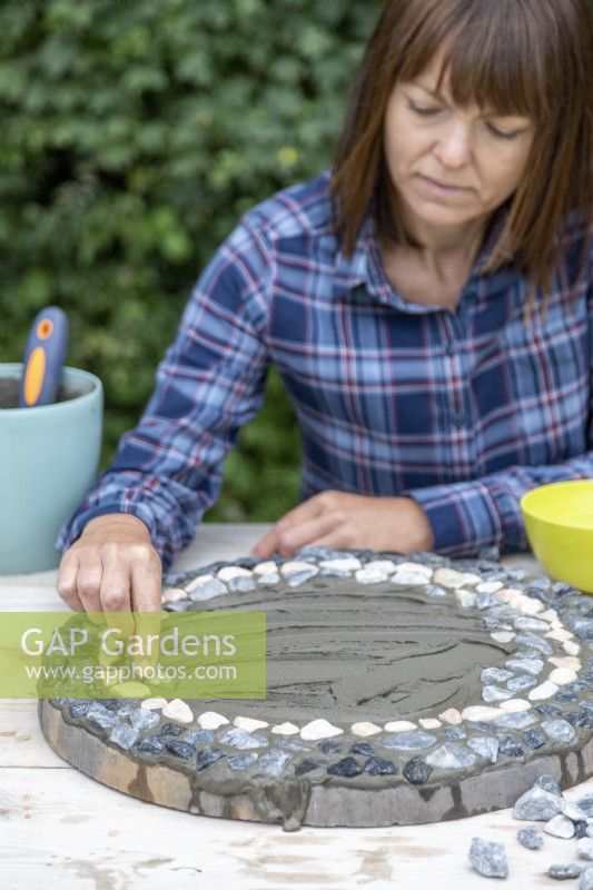 Woman placing pebbles on the grout