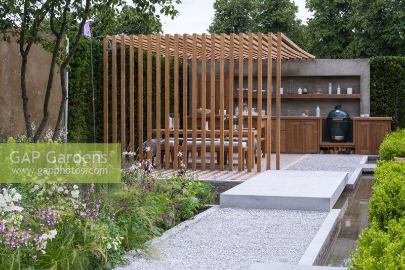 The Viking Friluftsliv Garden. A path flanked by a rill leads to a pergola built from iroko, for al fresco meals and outdoor kitchen. A multi-stemmed amelanchier shades a bed of grasses, astrantias, coneflowers, salvias, gaura and thalictrum.