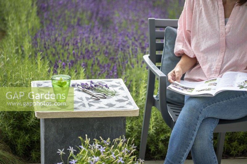 Woman sat next to stone slab table reading a magazine