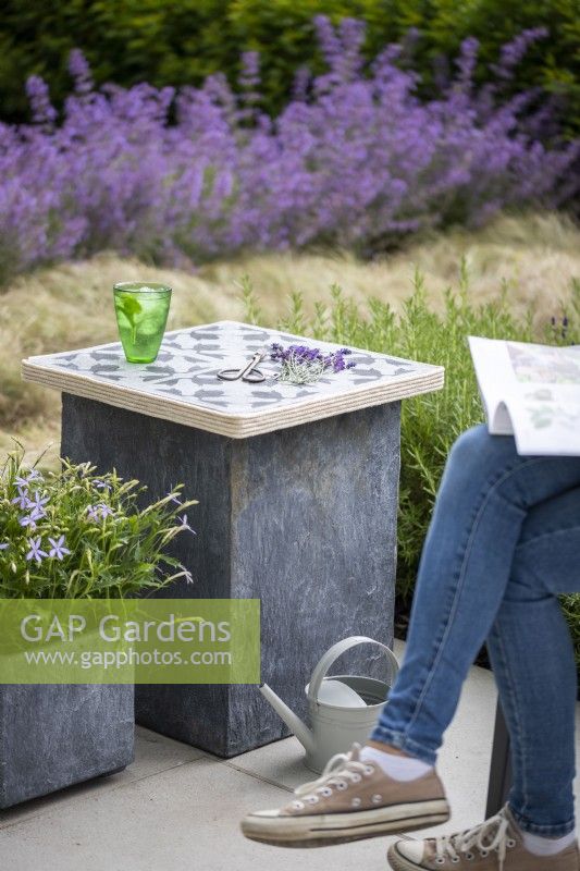 Stone slab table in a garden setting with woman reading magazine
