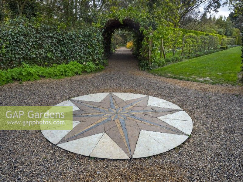 Paved decorative stone compass on gravel surface. Old Vicarage gardens East Ruston Norfolk