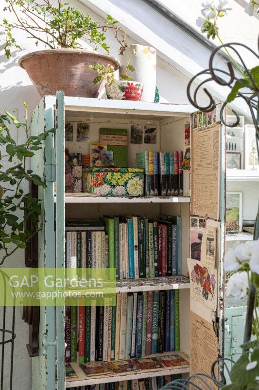 Conservatory bookcase filled with gardeners books, pots and gardening paraphanalia 