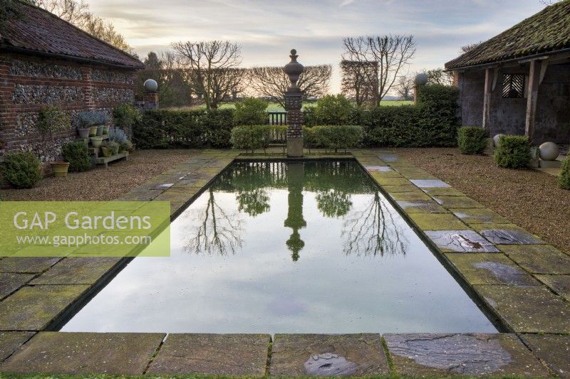 The pool garden, with its rectangular pool edged with paving and classical urn on a flint plinth forming a focal point at the end.
