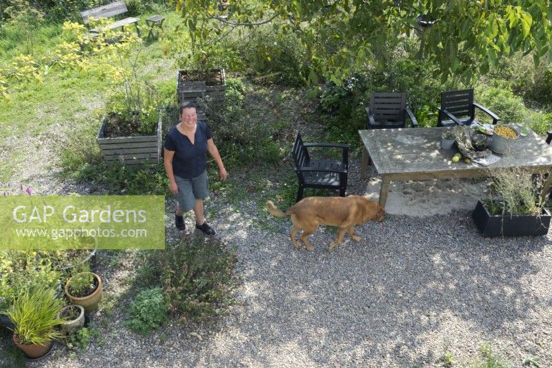 Anita van Zantvoort owner tea garden: 'Under the green heaven' and her dog. Overview with plants in containers.