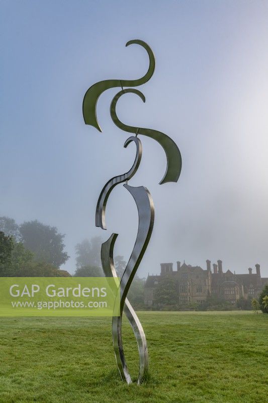 Contemporary kinetic metal sculpture on a garden lawn in summer - July