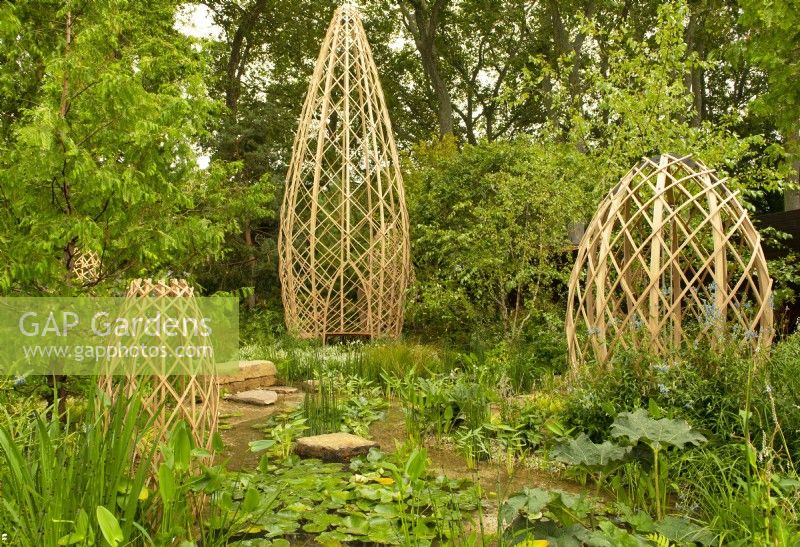 Four laminated bamboo structures surrounded by a pool filled with aquatic plants set in a woodland dell in the Guangzhou China: Guangzhou Garden, winnder of the best show garden award.