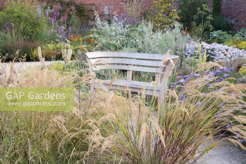 Autumn view of the Mediterranean area in the contemporary walled  Paradise Garden. Planting includes Stipa calamagrostis and Aster pyrenaeus 'Lutetia' 