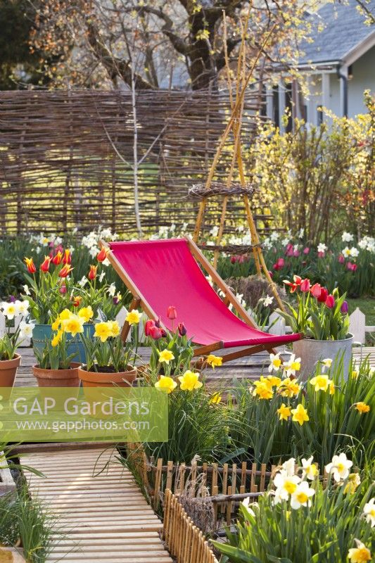 Deck chair on patio with spring flower containers.