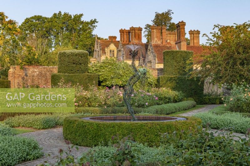 View of a contemporary figurative fountain in a formal country garden in autumn - September