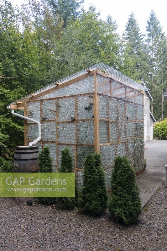 Greenhouse made from recycled glass bottles. Rainwater collection system for interior misting