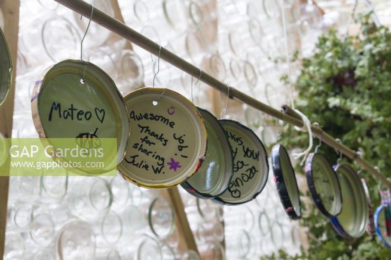 Lids of re-purposed glass jars are decorated,signed and displayed by community who visit