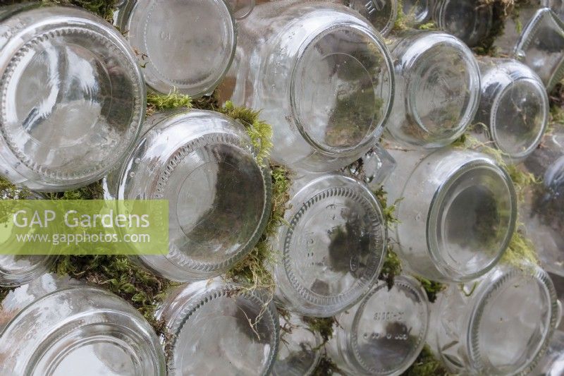 Moss gathered from garden used to pack spaces between glass bottles used to build walls of greenhouse