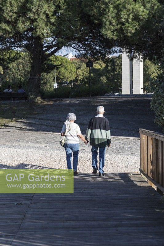 Senior couple holding hands and walking in the park. Lisbon, Portugal. September. 