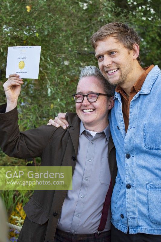 The M and G Garden. Garden designers Charlotte Harris and Hugo Bugg holding their Gold medal award aloft in front of the garden at the September 2021 Chelsea Flower Show.