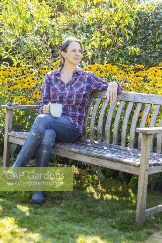 Woman sitting on a bench in front of Rudbeckias