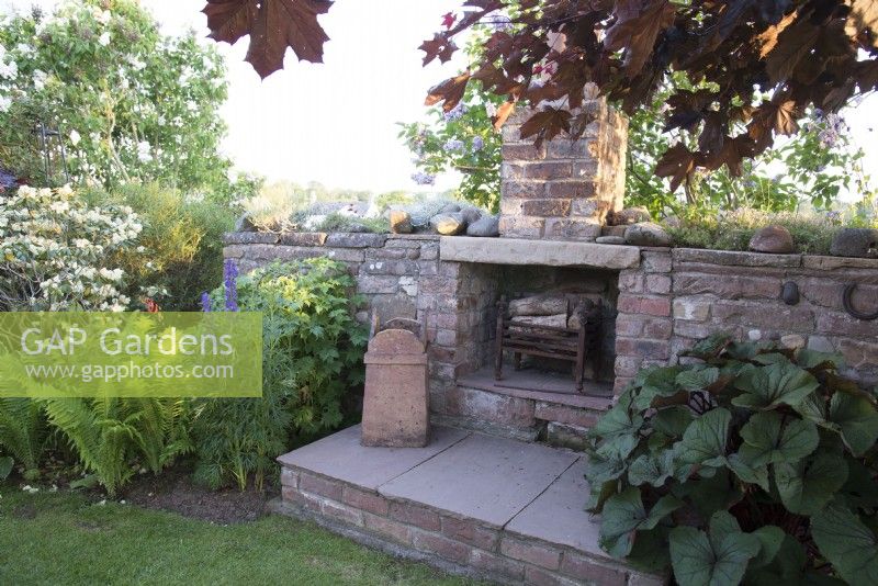 Stone fireplace built as a feature in cottage garden