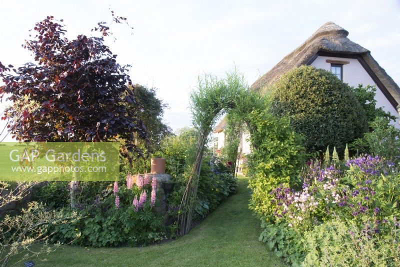 View of cottage garden with thatched cottage beyond