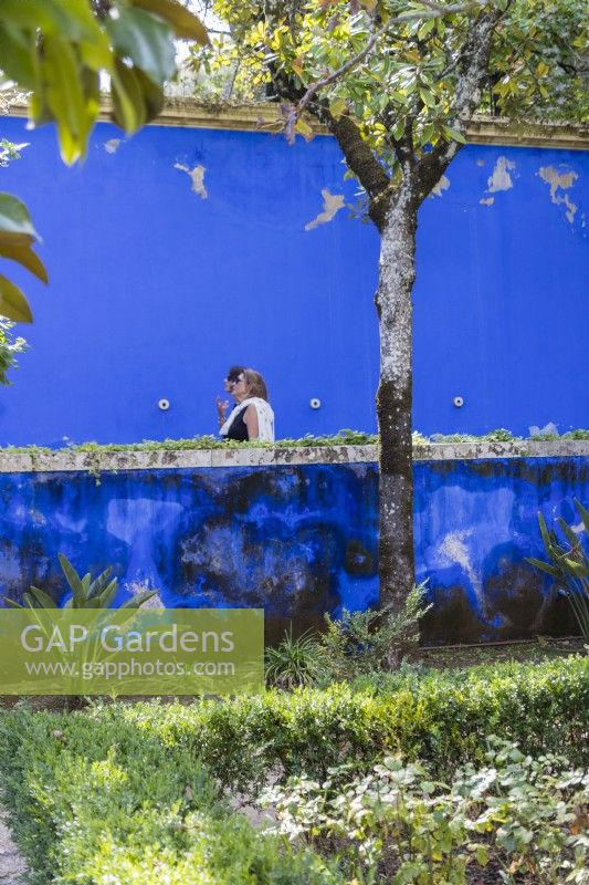 Distressed blue-painted walls of the Garden of Venus with two women visitors. Lisbon, Portugal, September.