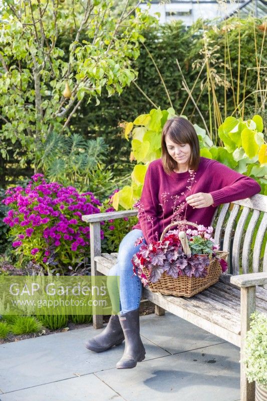 Woman sitting on a bench next to basket of plants