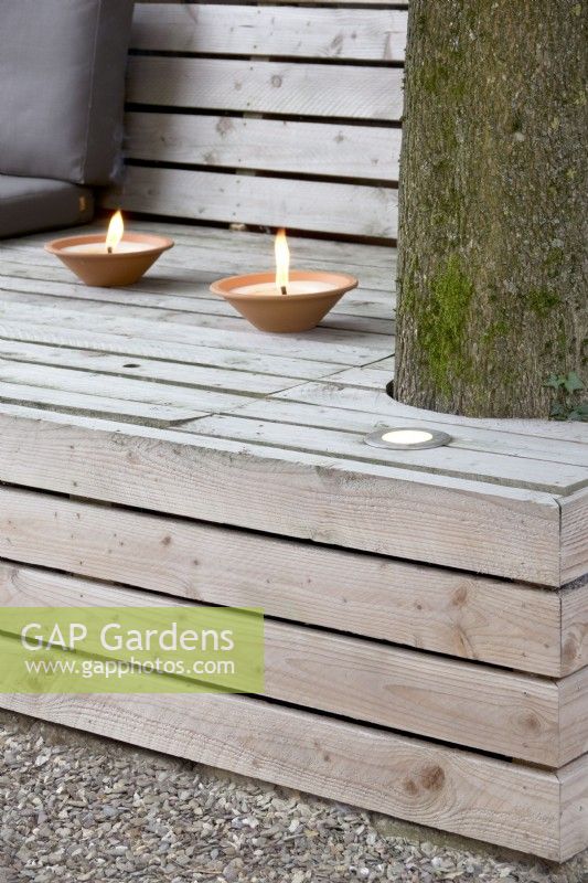 Two types of lighting on lounge bench, one insert plus candles in terracotta holders.
