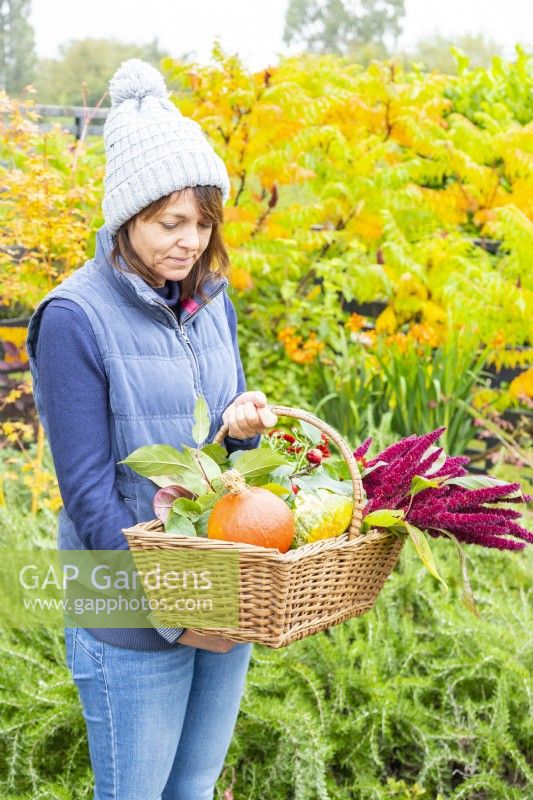 Woman holding a basket containing squashes and Amaranthus flowers