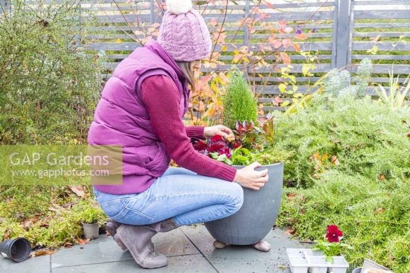 Woman planting bulbs in between the plants in the container