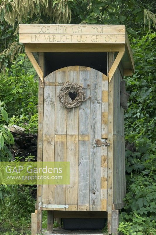 Wooden selfmade eco toilet in the garden with heart peephole.