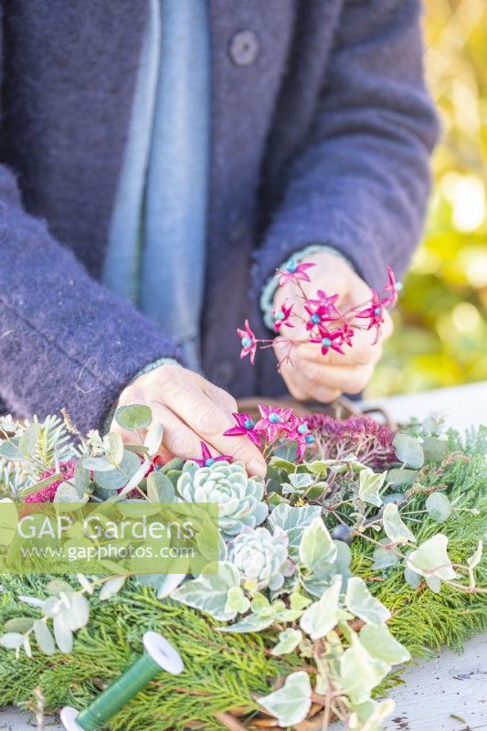 Woman adding Clerodendrum fruits to wreath