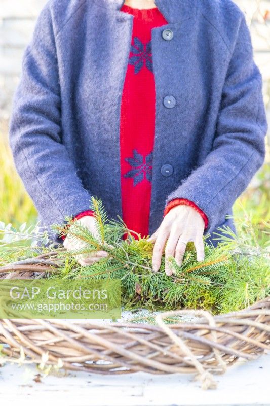 Woman adding Pine sprigs to wreath
