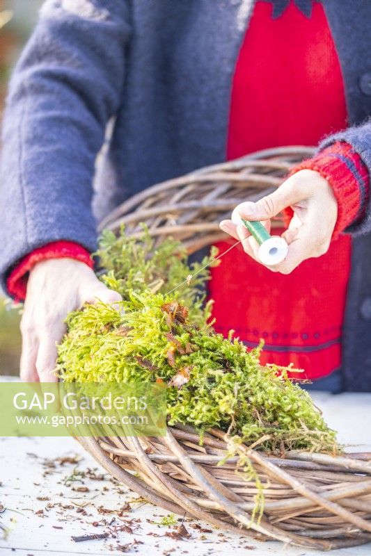Woman using wire to secure moss to the wreath