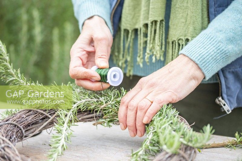 Woman using wire to secure Rosemary to the wreath