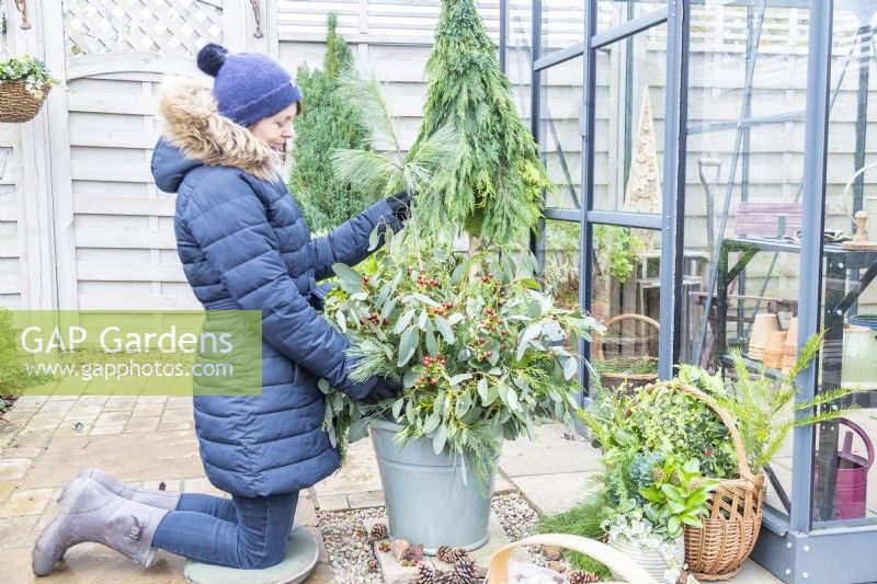 Woman placing pine sprig in the container