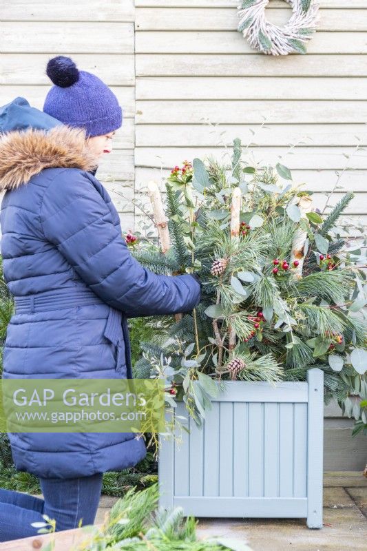 Woman placing sprigs with berries in the container