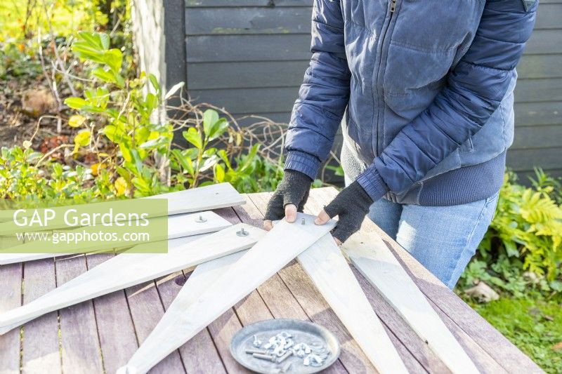 Woman using bolts and washers to begin to fix together the planks of wood in the shape of a star